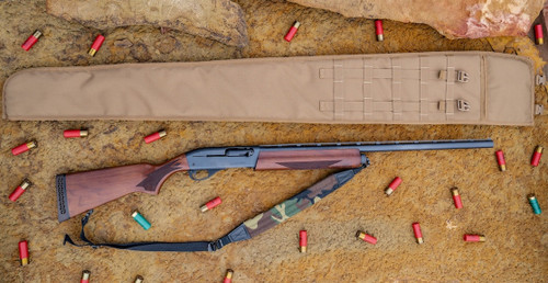 A Coyote Brown Shotgun Scabbard on a tan rock surface laying above a brown and black rifle with a camo strap attached to it and red and green shotgun shells scattered around it.